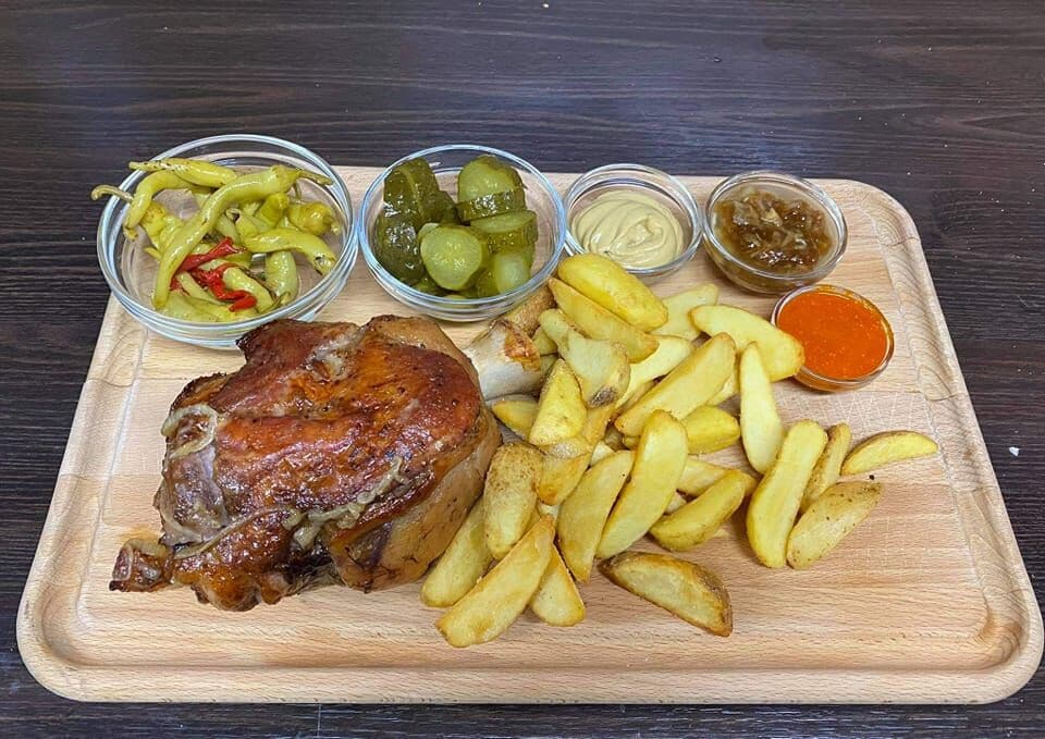 Pečené koleno s prílohami na drevenej doske